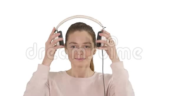 一个年轻的女人在白色背景下用耳机听音乐视频的预览图