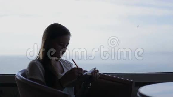 年轻漂亮女孩坐在咖啡馆里的剪影视频的预览图