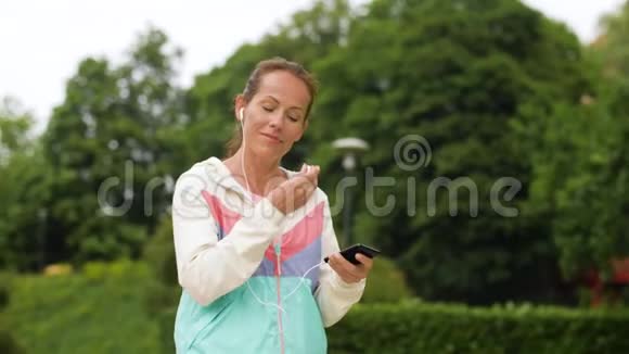 在公园里用智能手机播放音乐的女人视频的预览图