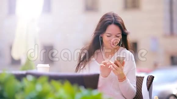 在欧洲城市的户外咖啡馆里年轻的白种人女人在传递信息和自我画像视频的预览图