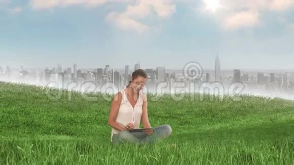 在城市旁边的田野里用平板电脑的女人视频的预览图