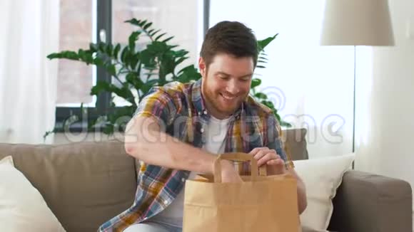 微笑的男人在家里打开外卖视频的预览图