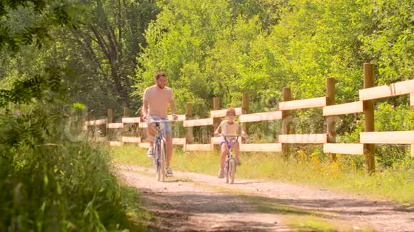 父亲和女儿在夏天公园骑自行车视频的预览图