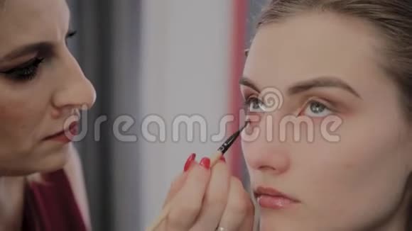 化妆师将专业化妆应用于一个美丽的年轻女孩化妆新概念视频的预览图