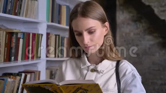 年轻严肃的女孩正在看书图书馆在后台视频的预览图