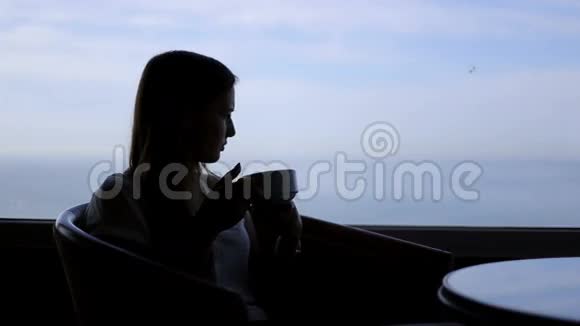小美女坐在咖啡馆里的剪影视频的预览图