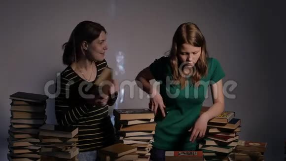 两个女孩母亲和她十几岁的女儿或者两个姐妹正在看书玩书4KUHD视频的预览图
