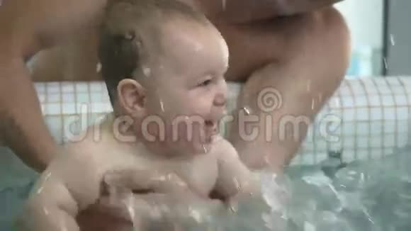 可爱的小男孩正把水溅在儿童游泳池里视频的预览图