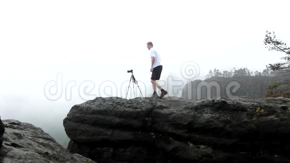 摄影师与三脚架站在岩石的观点和拍摄雾蒙蒙的早晨景观萨克森国家公园视频的预览图