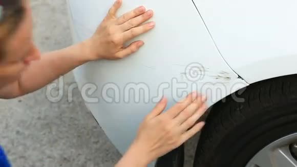 看着一辆损坏的车一位金发女子在车祸后检查汽车损坏视频的预览图