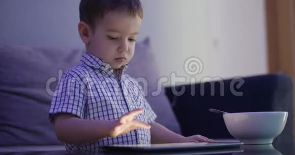 可爱的孩子用平板电脑娱乐小男孩把闲暇时间花在玩手游上把明亮的阳光压得粉碎视频的预览图