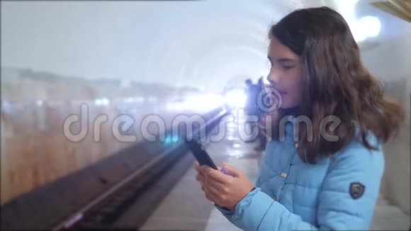 少女在地下地铁里乘地铁等待火车的到来手持智能手机小可爱视频的预览图