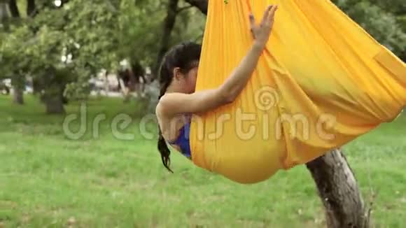 反重力瑜伽在公园里用吊床做瑜伽运动的女人视频的预览图