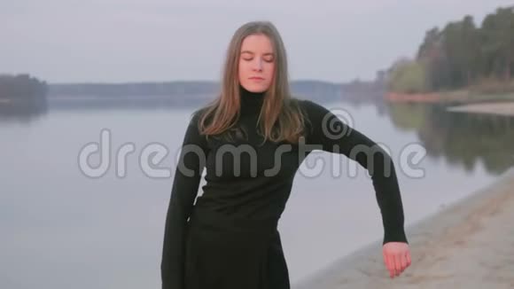 穿着黑色衣服的年轻漂亮女孩在河边跳舞剪影视频的预览图