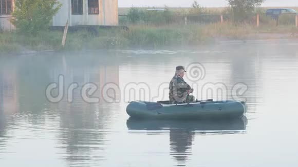 一艘充气船一个雄性渔夫在雾中的湖上一大早视频的预览图