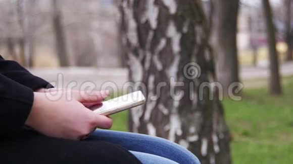 在城市公园的长凳上用手机的年轻女孩视频的预览图