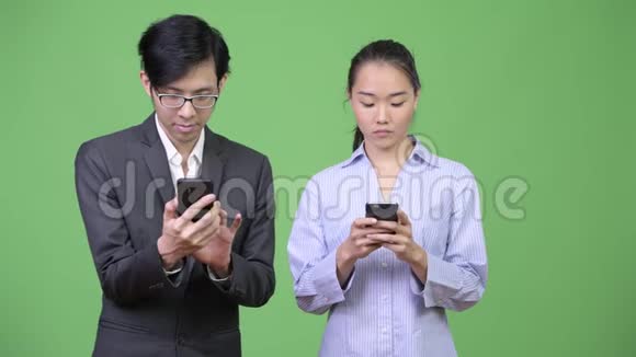 年轻的亚裔商业夫妇一起使用电话视频的预览图