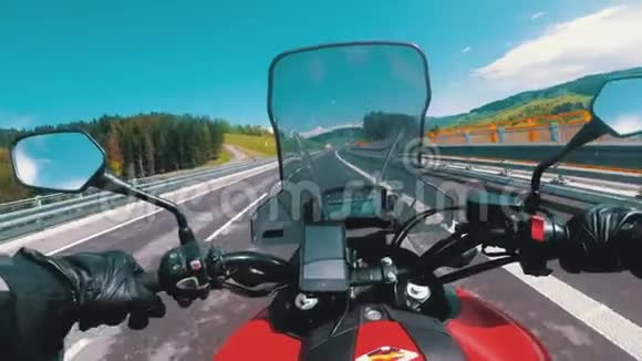 骑在空公路上的摩托车手从摩托车车轮后面看POV视频的预览图
