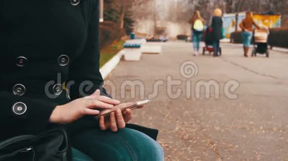 在城市公园的长椅上使用智能手机的年轻女性视频的预览图