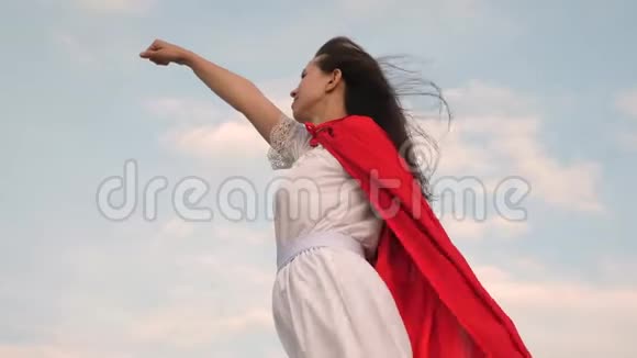 女孩梦想成为超级英雄美丽的超级英雄女孩站在田野上穿着红色斗篷披风飘扬视频的预览图