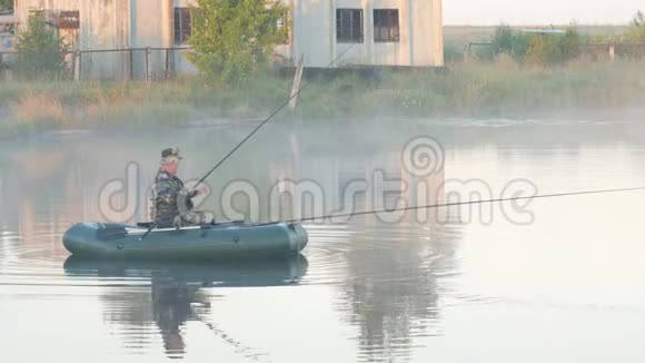 一艘充气船一个雄性渔夫在雾中的湖上一大早视频的预览图
