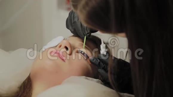 一个非常漂亮的女孩在美容院做一个层叠睫毛美容师做睫毛手术视频的预览图