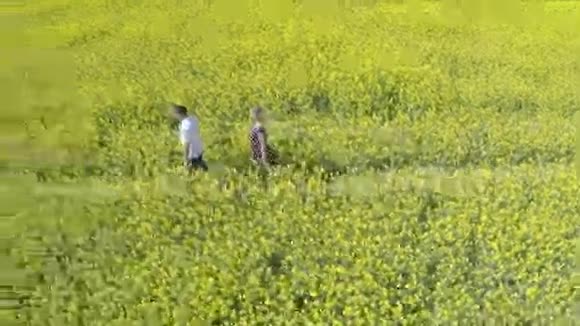 深情的男人和女人牵着手在油籽农场跑步视频的预览图