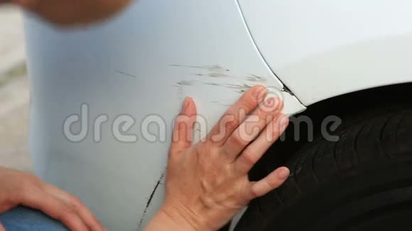 看着一辆损坏的车一位金发女子在车祸后检查汽车损坏视频的预览图