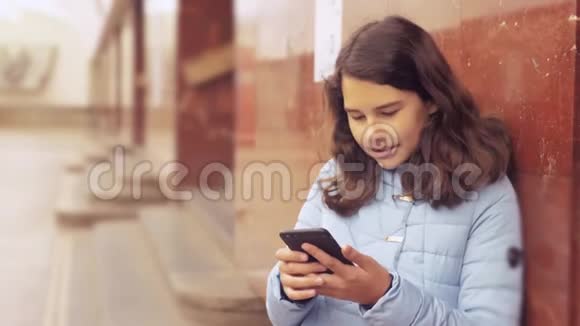 少女在地下地铁里坐地铁等待火车的到来手持生活方式智能手机视频的预览图