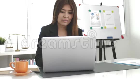 漂亮的亚洲商务女性在现代办公室里用笔记本电脑工作视频的预览图