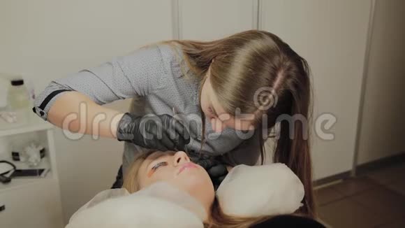 一个非常漂亮的女孩在美容院做一个层叠睫毛美容师做睫毛手术视频的预览图