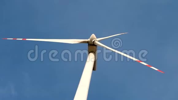 在蓝天背景上旋转风车螺旋桨的叶片风力发电纯绿色能源视频的预览图