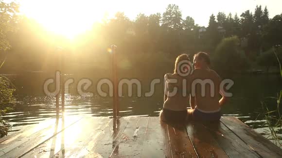 日落时分浪漫的情侣坐在河边接吻视频的预览图