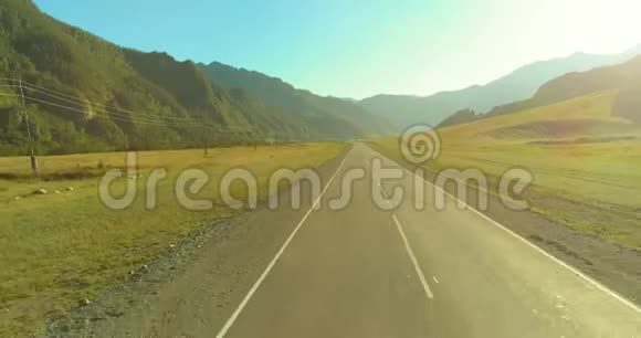 在阳光明媚的夏季早晨低空飞越山路和草地视频的预览图