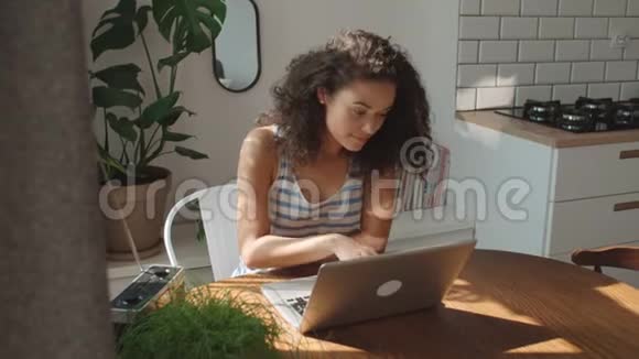 迷人的年轻女人在家里用笔记本电脑打字视频的预览图