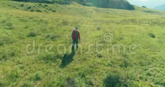 乘坐背包旅行徒步旅行游客步行穿过绿色的山野夏日的乡村山谷视频的预览图