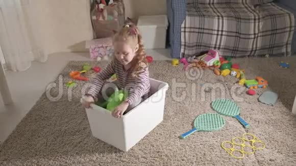 可爱的笑着的小男孩学龄前的金发女郎在一个白色的盒子里玩五颜六色的玩具坐在地板上视频的预览图