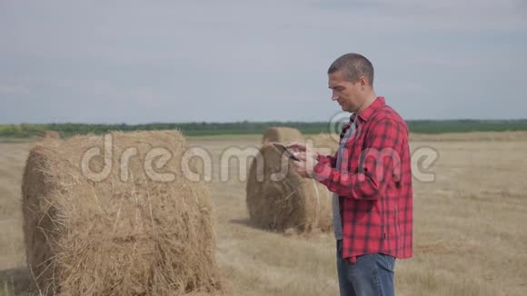 智慧农业概念生活方式一名农民工人在数字平板电脑上的田野里研究干草堆慢慢慢慢视频的预览图