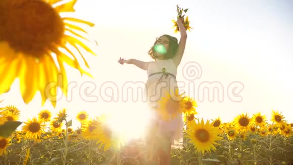 可爱的女孩在黄色的花园向日葵阳光在夏天美丽的日落小女孩向日葵的生活方式视频的预览图
