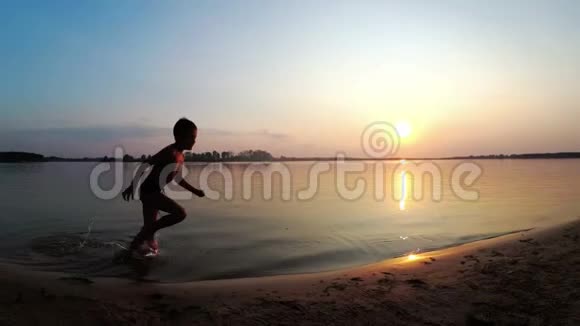 日落时沿着海滩奔跑的快乐儿童剪影慢动作视频的预览图