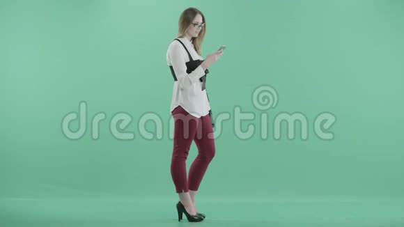 一位年轻女子手里拿着电话站着视频的预览图