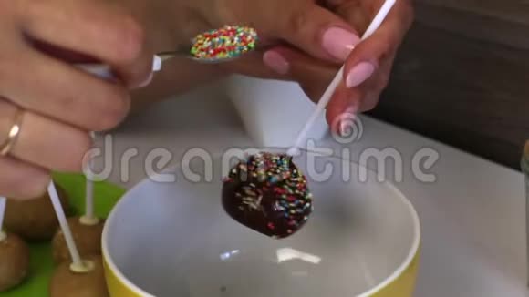 一个女人在黑巧克力中洒满了彩色调料的波普蛋糕桌子上的下一个是蛋糕的空白视频的预览图