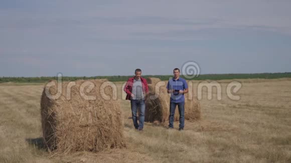 团队农业智慧农业生活方式理念两个男的农民工人走在田野上的草堆上视频的预览图