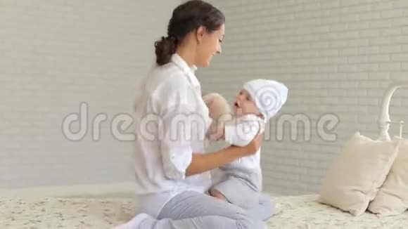 一位年轻的母亲在床上家里抱着一个新生儿的肖像视频的预览图