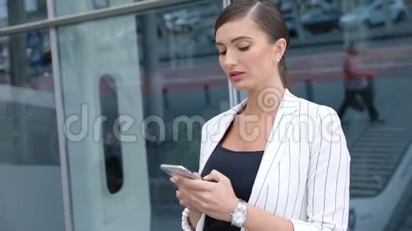 漂亮的商务女性在户外办公室附近打电话视频的预览图