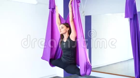 年轻漂亮的女孩在健身房练习空中瑜伽视频的预览图