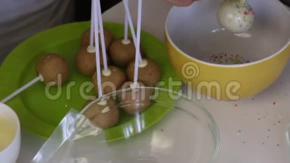 一个女人在彩色的衣服上洒上白巧克力的波普蛋糕桌子上的下一个是做流行蛋糕的原料视频的预览图