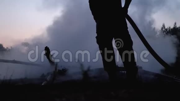 用灭火器用水灭火消防队员拿着水管晚上扑灭森林篝火视频的预览图