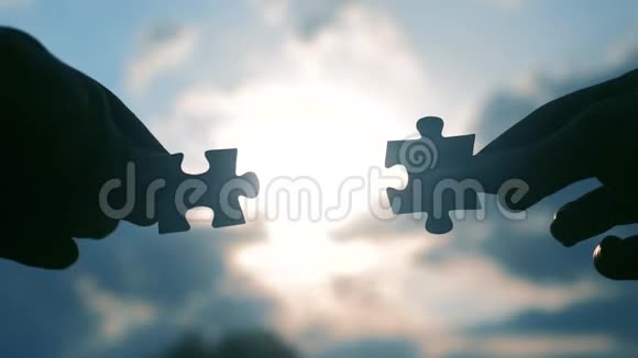 团队合作商业金融理念男性手连接两个拼图剪影与日落象征团队合作视频的预览图
