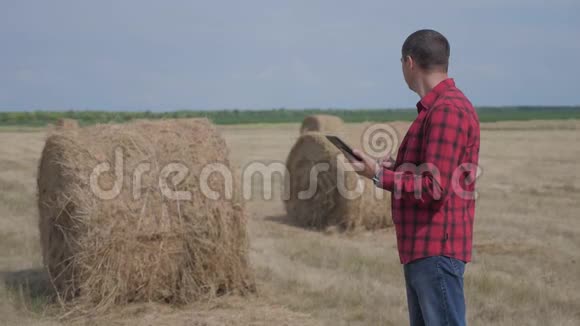 智慧农业理念生活方式男子工人农民在数字平板电脑上的田野上研究干草堆慢慢慢慢视频的预览图